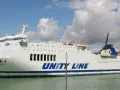 Biały prom Galileusz z napisem "UNITY LINE" cumuje w porcie.