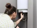 Donna controlla il suo scaldabagno da 50 litri, verificando il tempo di riscaldamento.