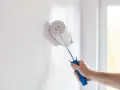 Mano pintando pared blanca con rodillo. Creando diseños de paredes pintadas con cinta para un acabado perfecto.