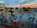 Terrazza di un ristorante al tramonto, con tavoli apparecchiati e fiori rossi. Un invito a scoprire il **vecchio palmento menu**.