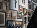 Un mur couvert de tableaux, dont des portraits de Marilyn Monroe, une scène de rue et une affiche de Spider-Man, le tout dans un cadre.