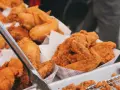Un surtido de crujiente pollo frito en recipientes de cartón. Las piezas doradas y sabrosas invitan a disfrutar de este clásico.