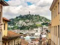 Widok na wzgórze z pomnikiem w Quito, stolicy Ekwadoru. Kolorowe budynki i wąskie uliczki tworzą malowniczy krajobraz.