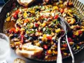 Pyszna caponata z selera z migdałami i oliwkami, podana w metalowej misie z pieczywem.