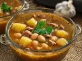 Dos cuencos de cristal con caldo gallego, patatas, alubias y carne.