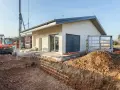 Budowa domu 70m2. Wykop pod fundamenty, koparka i częściowo wykończony budynek.