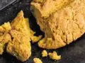 Goldgelbes, rustikales Brot, das nach Rezepten mit Lupinen aussieht, liegt auf einem dunklen Blech.