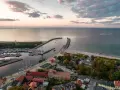 Widok z lotu ptaka na port w Ustce z łodziami i latarnią morską w tle.