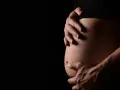Mani che accarezzano un pancione. La ricerca sulle cause dell'autismo in gravidanza è complessa e in continua evoluzione.