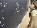 Dziewczynka zmagająca się z zadaniem z matematyki na tablicy. Czy dysleksja a matematyka to trudne połączenie?