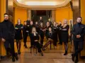 Grupa profesjonalistów w czarnych strojach pozuje w eleganckim wnętrzu.