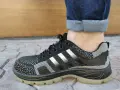 Czarne buty sportowe z białymi paskami i podwiniętymi nogawkami jeansów. Idealny przykład, jak podwinąć spodnie.