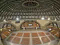 Wnętrze Hali Stulecia podczas zwiedzania. Widok na betonową kopułę, łuki i rzędy pomarańczowych krzeseł.