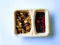 Dwie przegródki pojemnika: jedna z granolą i orzechami, druga z jagodami i truskawkami. Czy kasza jaglana ma gluten? Ta granola wygląda na bezglutenową!