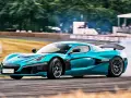 Niebieski Rimac Nevera, najszybsze auto elektryczne, driftuje na torze, wzbijając tumany dymu.