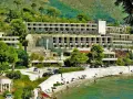Opuszczone hotele Chorwacja, zniszczone budynki hotelowe na wzgórzu, plaża z ludźmi i morze.
