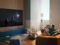 Familj tittar på en rymdfilm på TV:n, kanske via iptv tele2. En astronaut står framför en futuristisk stad under en solförmörkelse.