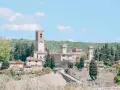 La Badia a Passignano, un borgo medievale toscano con un'imponente torre dell'orologio, circondato da colline verdi e cipressi.