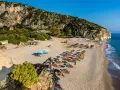 Piękne albania plaże z rzędami parasoli i leżaków, skaliste zbocze i turkusowe morze.