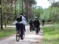 Grupa rowerzystów w lesie. Słońce przebija się przez drzewa, a ścieżka jest piaszczysta. To świetny sposób na spalenie puste kalorie i cieszenie się naturą.