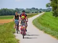 Rodzina na rowerach przemierza malownicze trasy rowerowe Małopolska. Słońce, zieleń i uśmiechy na twarzach.