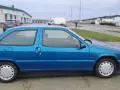 Niebieski Citroen ZX stoi na parkingu. W tle widać budynki i białą ciężarówkę.