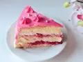 Pyszny tort malinowy z różowym lukrem i srebrnymi perełkami, przełożony kremem i malinową konfiturą.