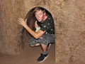 Młody mężczyzna kuca w wąskim tunelu, jednym z historycznych Cu Chi Tunnels.
