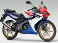 Sportowy motocykl Honda CBR 125R w barwach V-Max, z czerwonym, białym i niebieskim malowaniem.