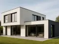 Nowoczesny dom z płaskim dachem, z dużymi przeszkleniami i minimalistyczną bryłą, otoczony zielonym trawnikiem.