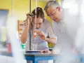 Schülerin bei chemischem Experiment mit Lehrer. Perfekt für die Ausbildung mit Abitur NRW.