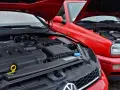 Dwa czerwone Volkswageny z otwartymi maskami. Nowszy model z silnikiem TDI obok starszego, gdzie widać stary diesel.