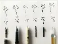 Ejemplos de trazos y formas básicas en dibujos con tinta china, junto a varias plumas y puntas de caligrafía.