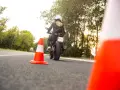 Kobieta na motocyklu podczas egzaminu na prawo jazdy kat A. Sprawdza cenę kursu.