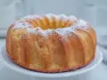 Najlepsza babka cytrynowa wilgotna na oleju, oprószona cukrem pudrem, prezentuje się apetycznie na białej paterze.