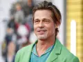 Brad Pitt, attore famoso, sorride con un completo verde acceso.