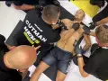 Zawodnicy w macias high league po walce, jeden z nich leży na macie, otoczony przez ratowników medycznych.