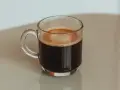 Kawa po kolonoskopii, w szklanej filiżance, z pianką na wierzchu.