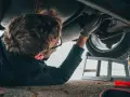 Mechanik bada podwozie auta, szukając objawów awarii elektrozaworu skrzyni biegów.