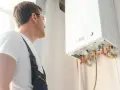 Instalator sprawdza kocioł gazowy, przygotowując dom na nadchodzący sezon grzewczy.