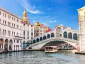 Venezia, il Canal Grande con il Ponte di Rialto e il Fondaco dei Tedeschi sullo sfondo. Una motonave naviga sull'acqua.
