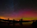 Ein atemberaubendes polarlicht tanzt über einem sternenklaren Himmel, reflektiert in einem ruhigen Gewässer.