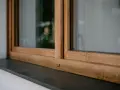 Drewniane okna w ciepłym kolorze okien winchester, z kamiennym parapetem.