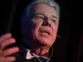 Emilian Kamiński, znany z wielu filmów, w eleganckim stroju z muszką, przemawia na scenie.