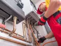 Instalator pracuje przy kotle gazowym, przygotowując go do zmiany właściciela. Dowiedz się, jak przepisać gaz na nowego właściciela PGNiG.