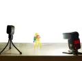 Une figurine Playmobil prend une photo avec un appareil sur trépied. Une autre caméra et un flash sont présents. Vue macro.