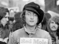John Lennon w czapce i okularach, trzymający plakat "Red Mole". W tle inni ludzie, być może fani jego utworów.