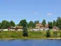 Gröna kullar med husbilar och röda stugor vid en sjö. En idyllisk plats för greans camping.