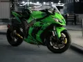 Japoński motocykl Kawasaki Ninja ZX-10R w jaskrawym zielonym kolorze, z kaskiem na siedzeniu, gotowy do nocnej jazdy.