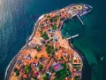 Wyspa z czerwonymi dachami i zielonymi boiskami, otoczona turkusową wodą. Idealna pogoda w Senegalu.